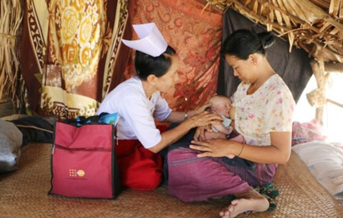 Daw Aye Myint examines a mother and her newborn in Zee Taw Pin Village